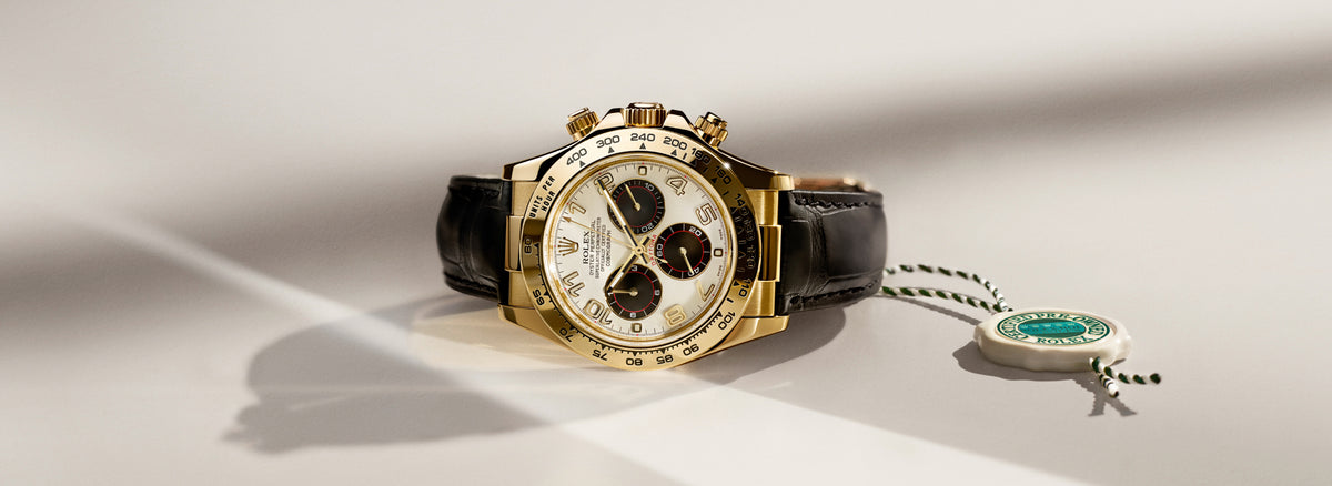 Rolex watch with a black strap and gold case on a light background