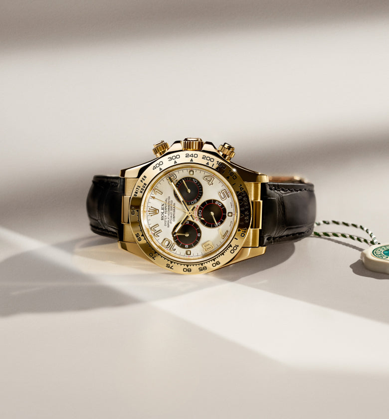 Rolex gold watch with black leather strap on a light background