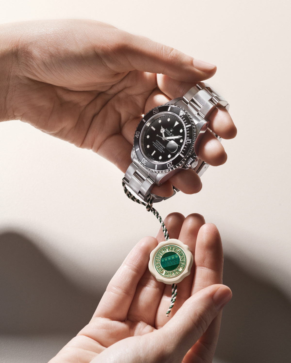 Person holding a Rolex wristwatch with a close-up of the Rolex Certified Pre-Owned swing tag