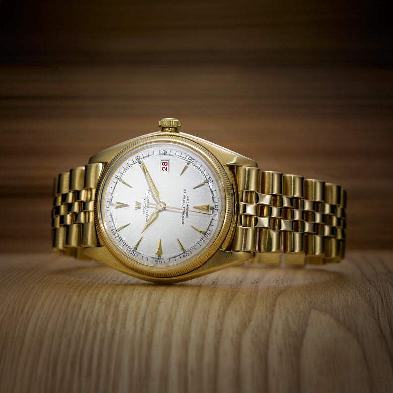 Rolex Gold wristwatch with a white dial on a wooden surface