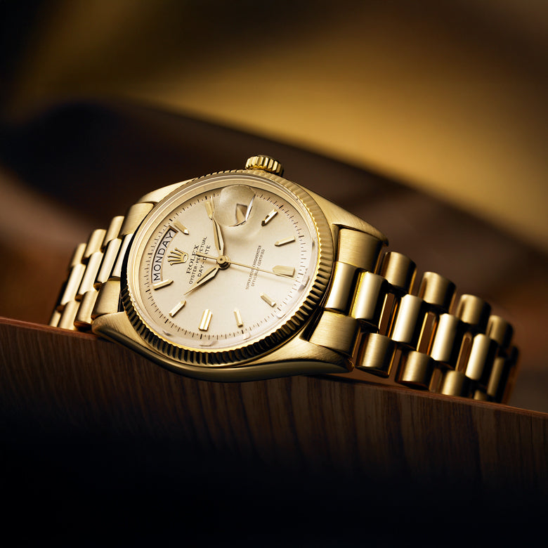 Rolex Day-Date gold wristwatch with a detailed face on a wooden surface