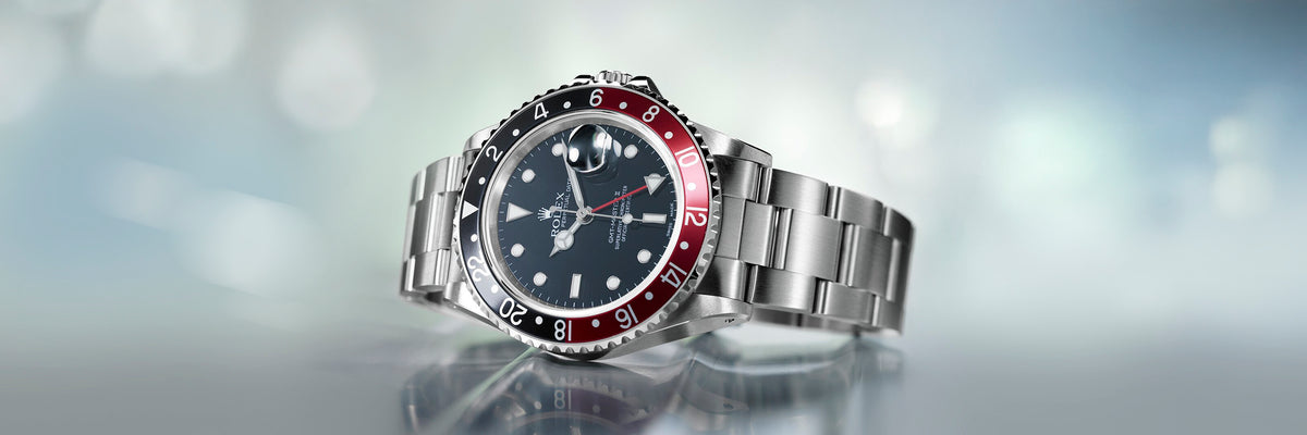 Rolex GMT Master II watch with a black and red bezel on a reflective surface