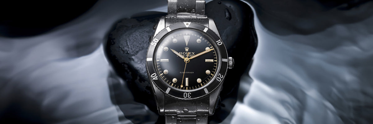 Rolex Submariner watch with black dial and silver case on a dark background