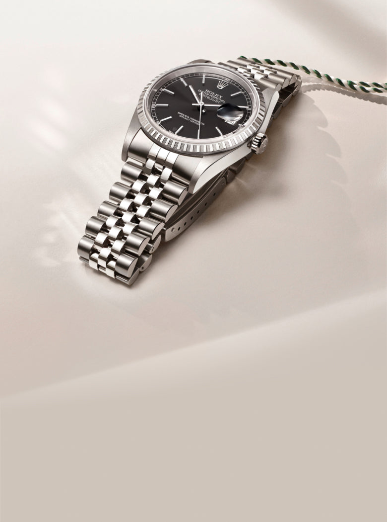 Rolex watch with a black face on a light beige background