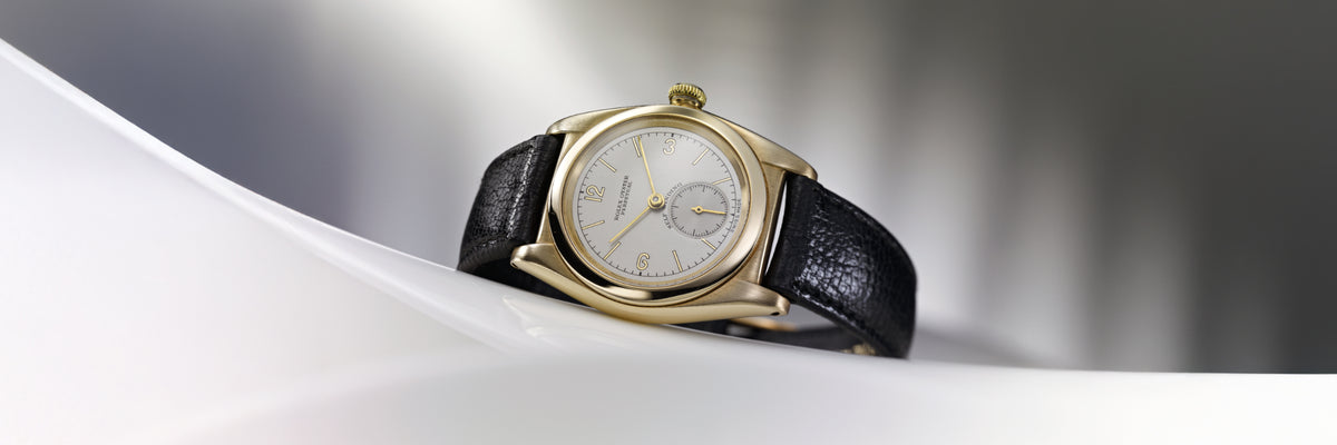 Rolex watch with black leather strap on a white surface