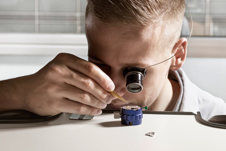 Rolex watchmaker examining a movement