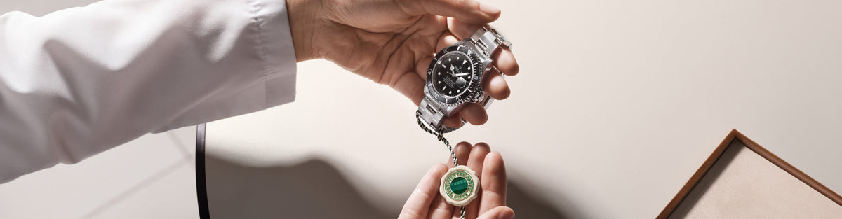 Person holding a silver watch with a black face.